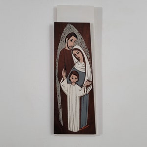 May include: A vintage illustration of a holy family with a brown background. The father is wearing a brown robe, the mother is wearing a blue robe with a white veil, and the child is wearing a white robe. The family is surrounded by a halo of light.