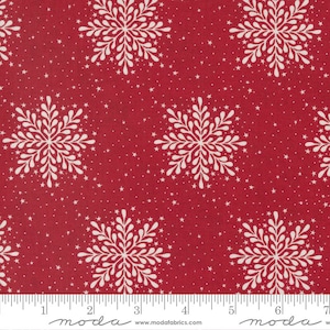 May include: Red fabric with a white snowflake pattern and small white stars. The fabric has a ruler with the word "moda" printed on it.