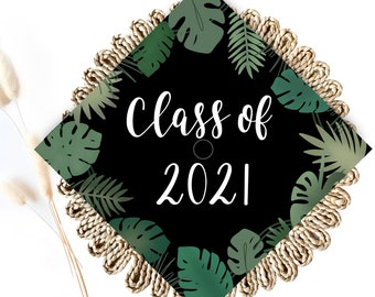 May include: Black graduation cap with a green tropical leaf pattern and the text "Class of 2021" in white.