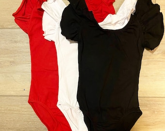 May include: Three leotards in red, white, and black with short puffed sleeves and snap closures.
