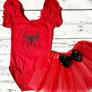 May include: Red and black spider-themed baby outfit with a red leotard with a black spider graphic and a red tulle skirt with a black sequin bow.