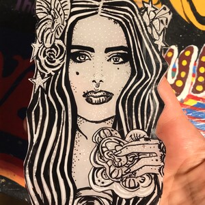 Peut inclure: Illustration en noir et blanc d'une femme aux cheveux longs et ondulés. Elle porte une couronne de fleurs et tient une grande fleur dans sa main. L'arrière-plan est une surface blanche mouchetée.