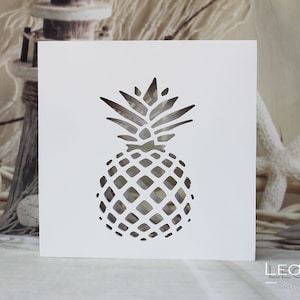 Könnte beinhalten: Weiße Karte mit einem Ausschnitt in Form einer Ananas. Die Ananas ist eine Silhouette mit einem detaillierten Design der Fruchtschale.
