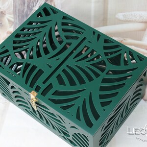 May include: A rectangular dark green wooden box featuring an intricate laser-cut leaf pattern on the lid and sides. The box includes a small gold-coloured metal latch on the front for closure. The brand name LEONARTS WOODEN DECOR STUDIO is visible.