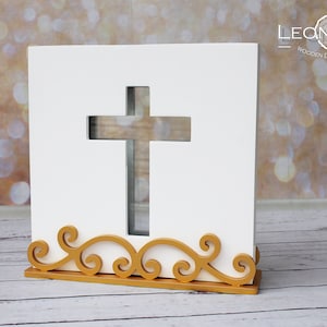Könnte beinhalten: Weiße Holzkiste in Kreuzform mit goldener Dekorbasis. Die Kiste hat einen Ausschnitt in Form eines Kreuzes. Die Kiste steht auf einer weißen Holzoberfläche. LEONARTS WOODEN DECOR STUDIO.