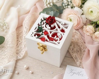 May include: A square white wooden box with a gold-coloured metal latch. The lid features an intricate white laser-cut floral pattern with a red rose and green leaves on top, revealing a red interior lining. The box is decorated with small red hearts.