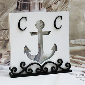 May include: White wooden box with a black anchor cutout and the letters "C C" on the front. The box has a black scrolled base.