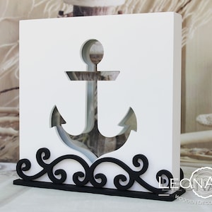 Puede incluir: Caja de madera blanca con un diseño de ancla recortada. El ancla es negra y tiene un diseño de desplazamiento decorativo en la parte inferior. La caja está etiquetada como "LEONARTS WOODEN DECOR STUDIO".