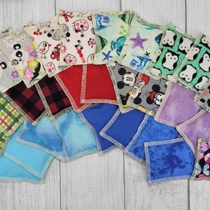 May include: A collection of 20 colorful fabric squares with various patterns, including cartoon characters, animals, and geometric designs. The squares are arranged in a semi-circle on a light wood surface.