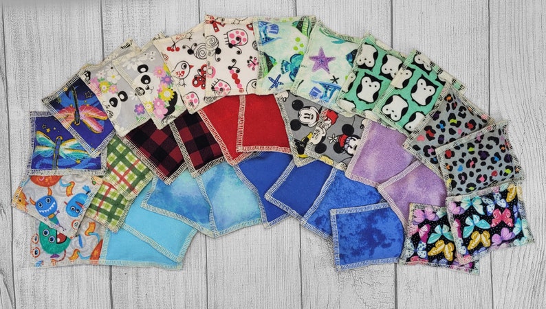 May include: A collection of 20 colorful fabric squares with various patterns, including cartoon characters, animals, and geometric designs. The squares are arranged in a semi-circle on a light wood surface.
