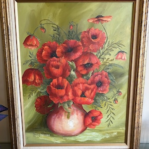 May include: Oil painting of a bouquet of red poppies in a pink vase, set against a green backdrop. The artwork is framed in a gold-colored, ornate frame. The painting is signed in the lower left corner.