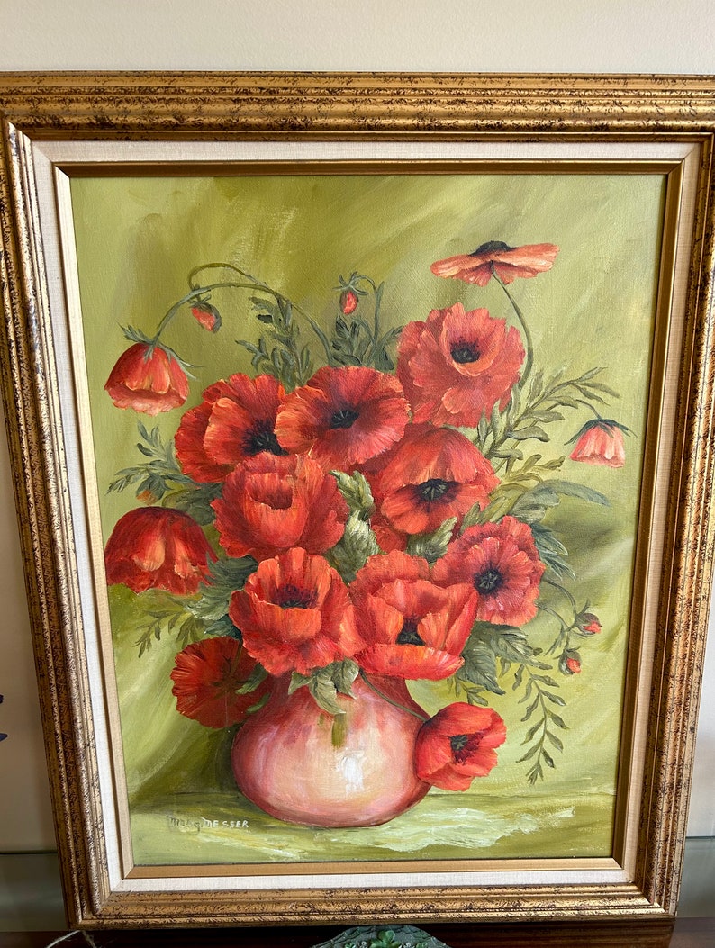 May include: Oil painting of a bouquet of red poppies in a pink vase, set against a green backdrop. The artwork is framed in a gold-colored, ornate frame. The painting has a vintage aesthetic.