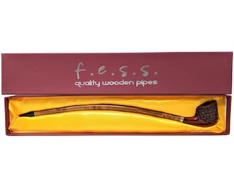 May include: A wooden smoking pipe with a curved stem and a brown bowl. The pipe is in a red box with the text "f.e.s.s. quality wooden pipes".