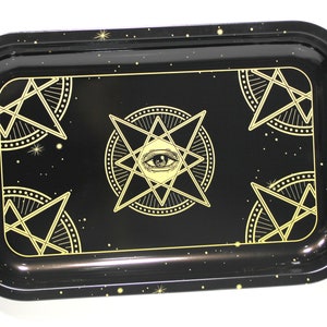 May include: Black metal tray with a gold design of stars and an all-seeing eye. The tray has a speckled black finish.