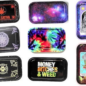 May include: Assortment of ten rolling trays with various designs. The trays are made of metal and feature different patterns, including a galaxy, tie-dye, a pentagram, and a marijuana leaf. Some trays have text, such as "Hail Sativa", "Money Bitches & Weed", and "The Stoner".