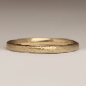 May include: A simple gold wedding band with a hammered finish.