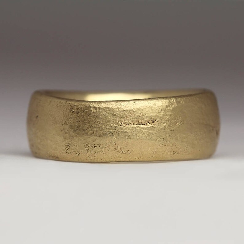 May include: A simple gold band ring with a textured finish.