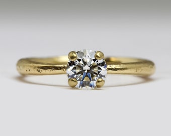 May include: A gold engagement ring with a round, clear diamond.
