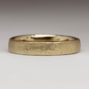 May include: A simple gold wedding band with a textured finish.