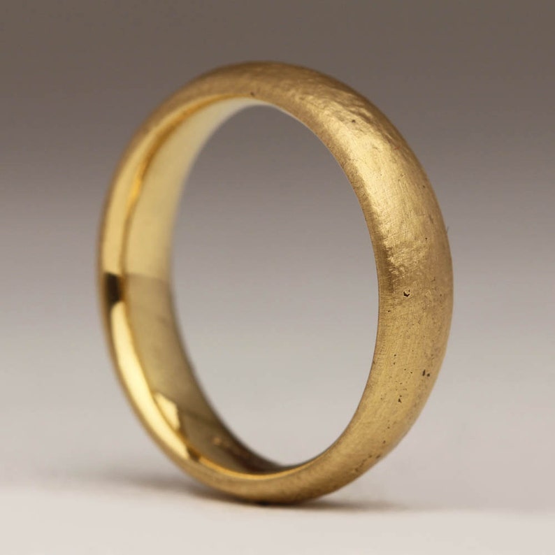 May include: A simple gold wedding band with a brushed finish.