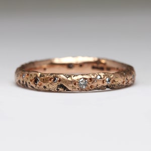 May include: A rose gold band ring with a textured surface and small diamonds set into the band.