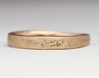 Op de afbeelding: Een eenvoudige, geborstelde gouden trouwring met een licht afgeronde rand.