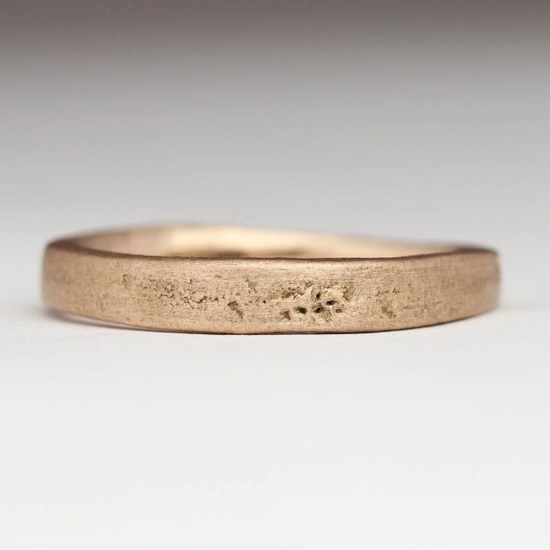 May include: A simple, brushed gold wedding band with a slightly rounded edge.