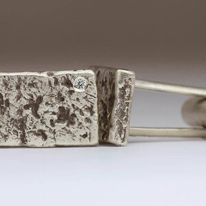 May include: Silver cufflinks with a textured finish and a small diamond accent.