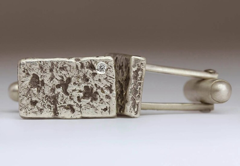 May include: Silver cufflinks with a textured finish and a small diamond accent.