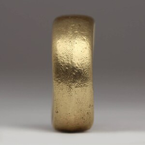 May include: A simple gold band ring with a smooth, slightly textured surface.