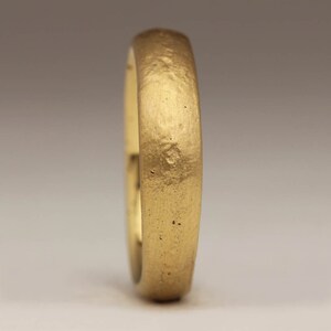 May include: A simple gold wedding band with a textured finish.