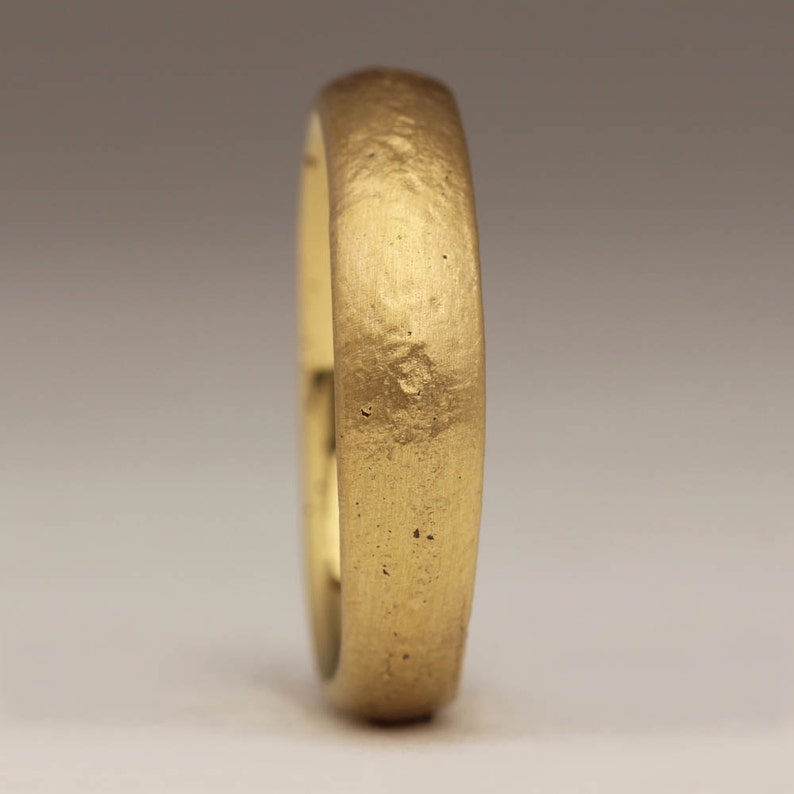 May include: A simple gold wedding band with a textured finish.
