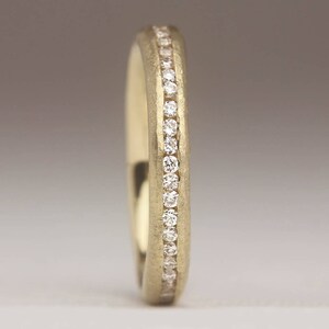 May include: A gold wedding band with a row of small diamonds set into the band.