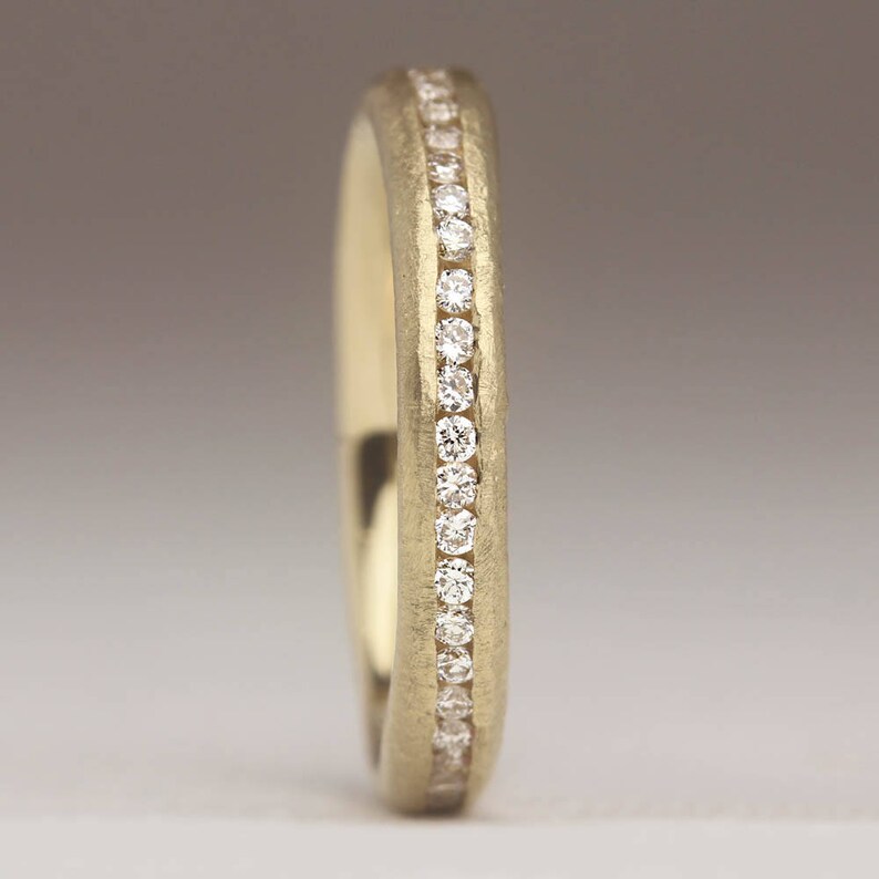 May include: A gold wedding band with a row of small diamonds set into the band.