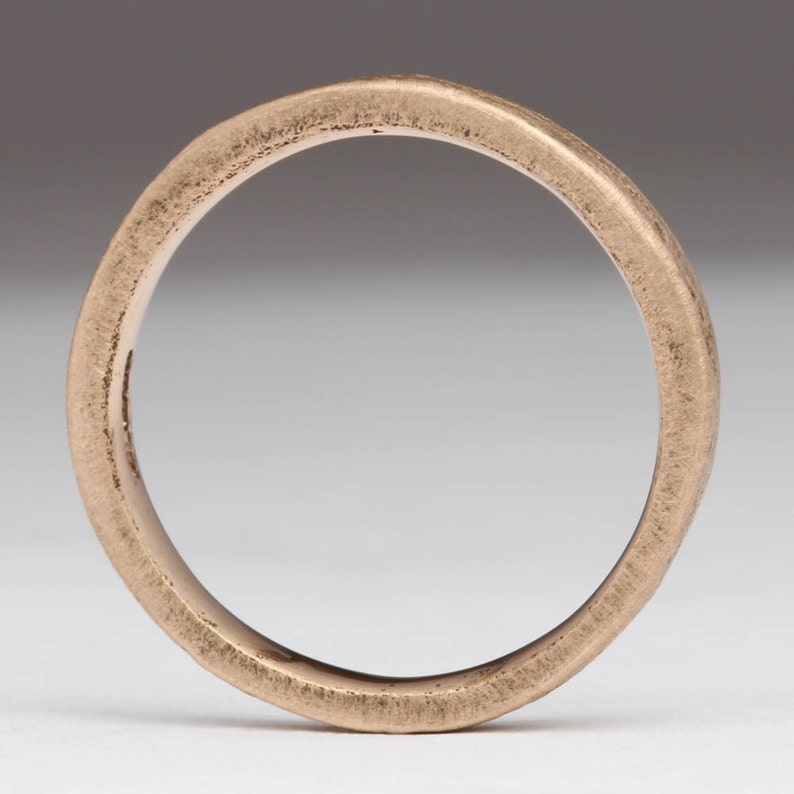 May include: A simple, brushed gold band ring.