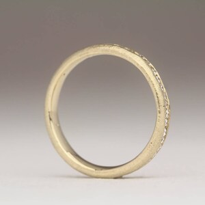 May include: A thin gold band with a row of small diamonds set into the metal.