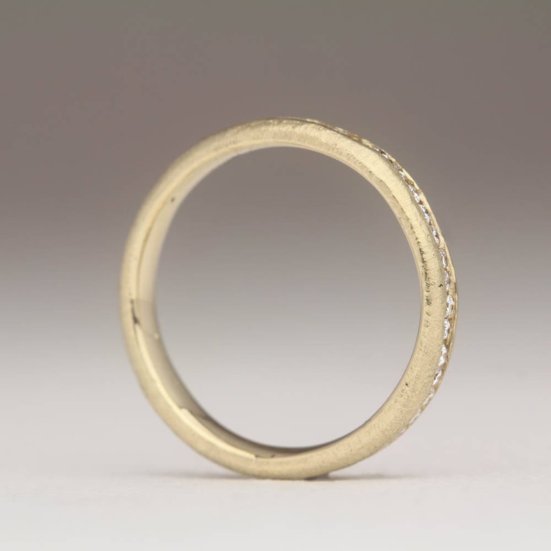 May include: A thin gold band with a row of small diamonds set into the metal.