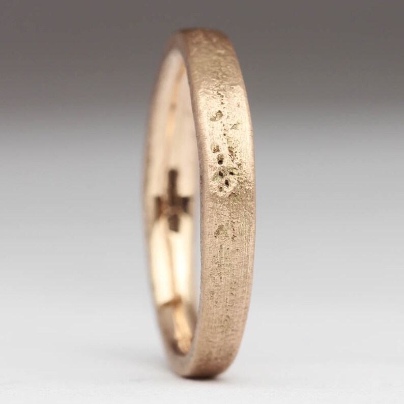 May include: A gold-colored ring with a textured surface. The ring is made of metal and has a simple design.