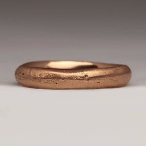 Op de afbeelding: Een eenvoudige, gladde koperen ring. De ring is glad en heeft een licht getextureerd oppervlak.