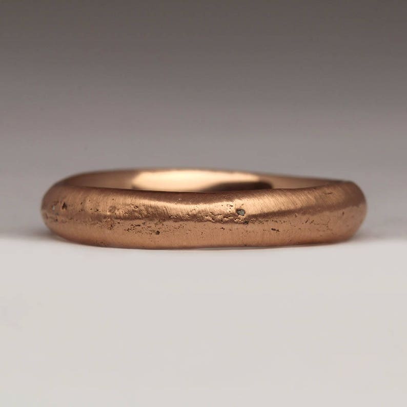 Op de afbeelding: Een eenvoudige, gladde koperen ring. De ring is glad en heeft een licht getextureerd oppervlak.
