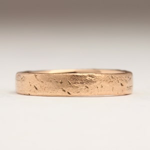 May include: A simple, textured rose gold wedding band.