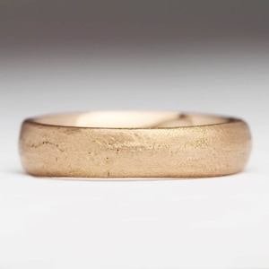 May include: A simple gold wedding band with a brushed finish.