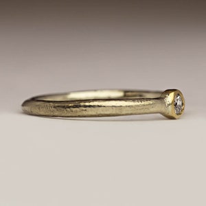 May include: A simple silver band ring with a small round diamond set in a gold bezel.