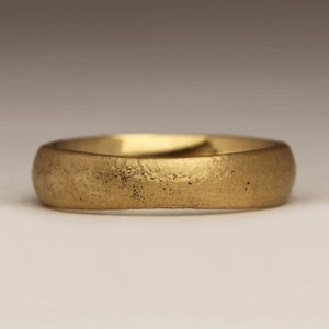 May include: A simple gold wedding band with a textured finish.