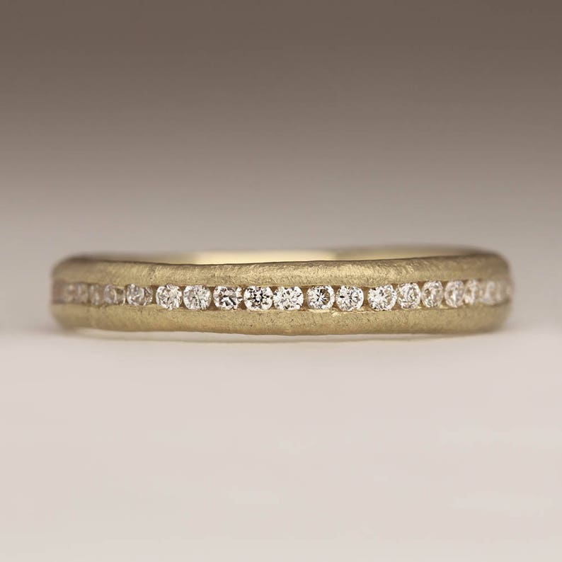 May include: A thin gold band with a row of small diamonds set in a channel setting.