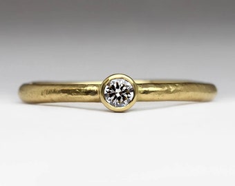 Könnte beinhalten: Ein einfacher Goldring mit einem einzigen runden Diamanten in der Mitte.