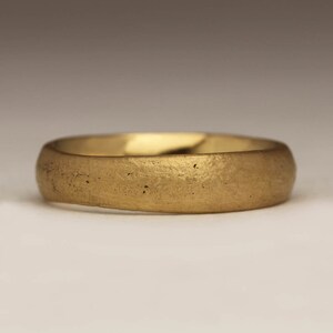 May include: A simple gold band ring with a smooth, slightly textured surface.