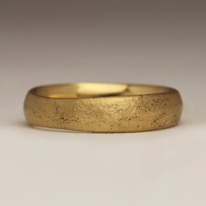 May include: A simple gold band ring with a textured surface.
