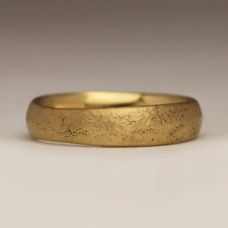 May include: A simple gold band ring with a textured surface.