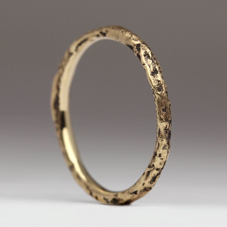 May include: A gold ring with a textured, hammered finish. The ring is simple and elegant, with a rustic look.